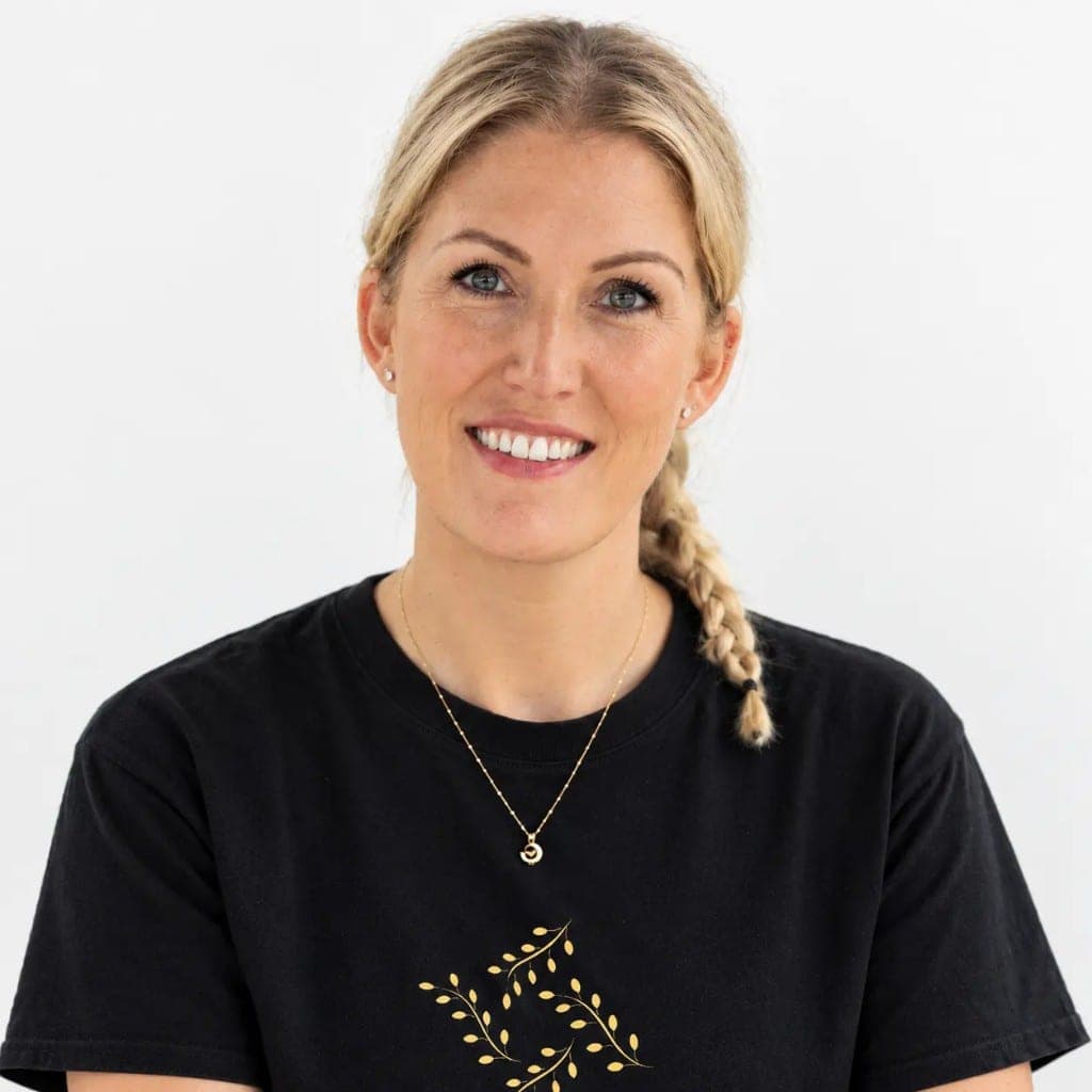 Becky smiling, wearing her Becky's Braids T-shirt, with her own hair in a side plait